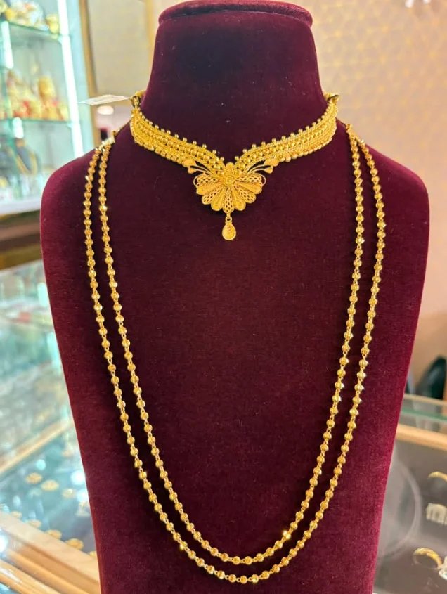 Double-strand long gold bead chain worn with a filigree gold choker